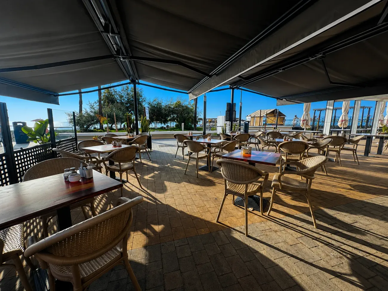 The Cafe American Bistro seafront terrace in Sabinillas, cream parasols open to the Mediterranean